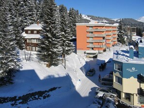 Ein Hotel mit mehreren Etagen, einem Parkplatz und verschneiter Umgebung.