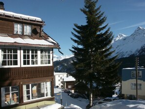 A two-story building with large windows, a wooden facade, and a snow-covered mountain in the background. - Chalet Willi-2.OG Appartement/Fewo, Dusche und Bad, WC, 6-Bettwohnung by Interhome (Arosa)