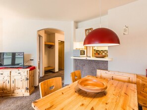 A compact living space with a dining table, chairs, a television, and a kitchen area with a microwave. - Galerie Obersee 1C by Arosa Holiday Appartement/Fewo, Bad, WC, 4-Bettwohnung by Interhome (Arosa)