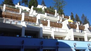 Ein mehrstöckiges Gebäude mit Balkonen, blauem Himmel und Bäumen im Hintergrund.
