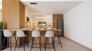 Cozinha moderna com ilha de madeira, banquetas e eletrodomésticos de aço inoxidável.