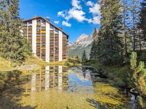 A multi-story hotel with balconies, a lake in front, and mountains in the background. - Rothornblick 44 by Arosa Holiday Appartement/Fewo,   Schöne 2½-Zimmerwohnung by Interhome (Arosa)