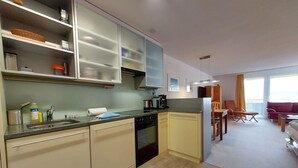 Una cocina moderna con lavavajillas, horno y comedor con mesa y sillas.