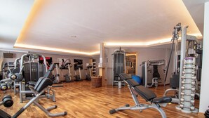 Un gimnasio con equipo de ejercicio variado, incluyendo cintas de correr, elípticas y zonas de levantamiento de pesas.