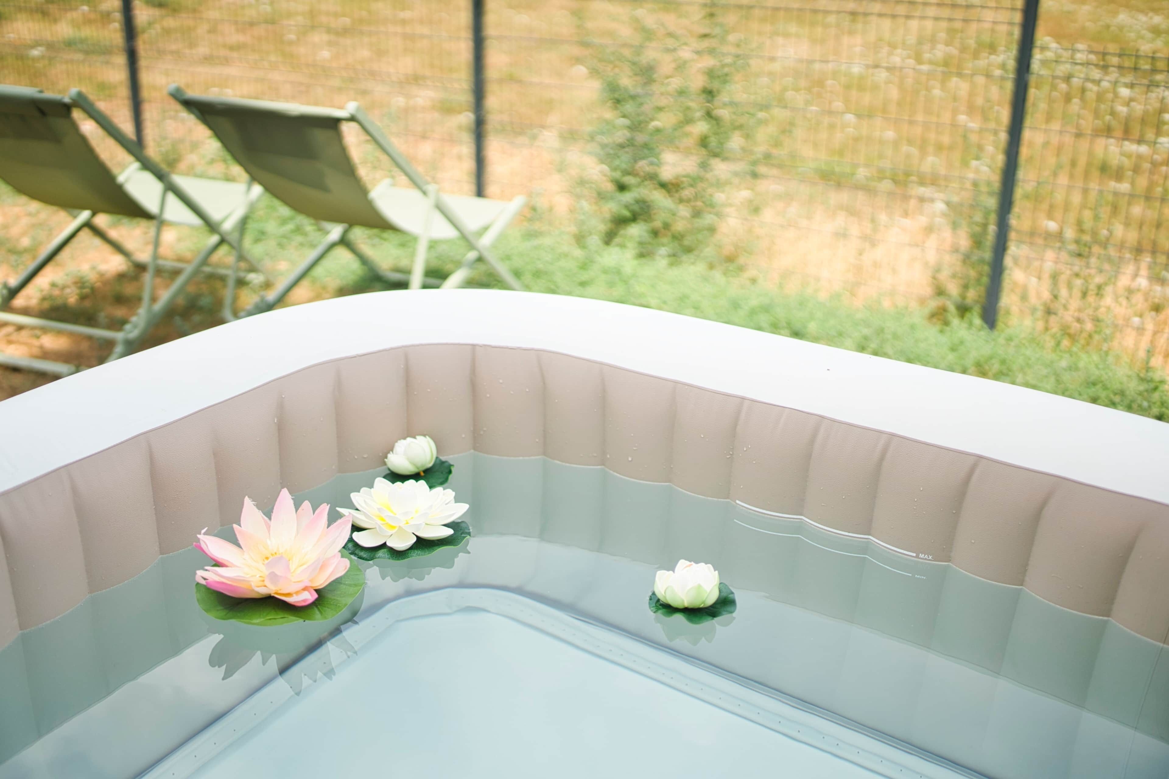 Een jacuzzi met waterlelies en uitzicht op een omheinde tuin.