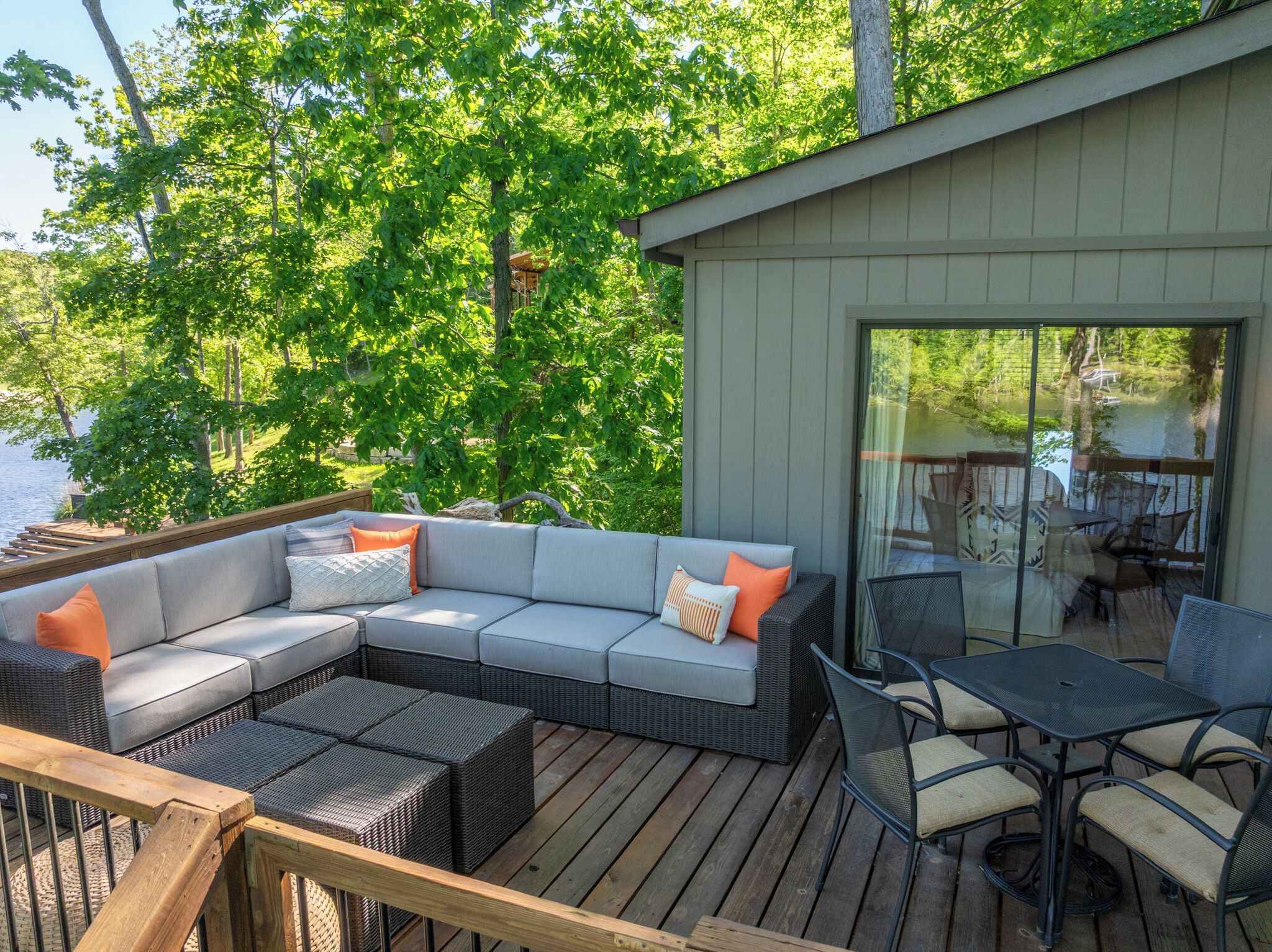 A deck with a sectional sofa, outdoor furniture, and a glass door leading to a patio area.
