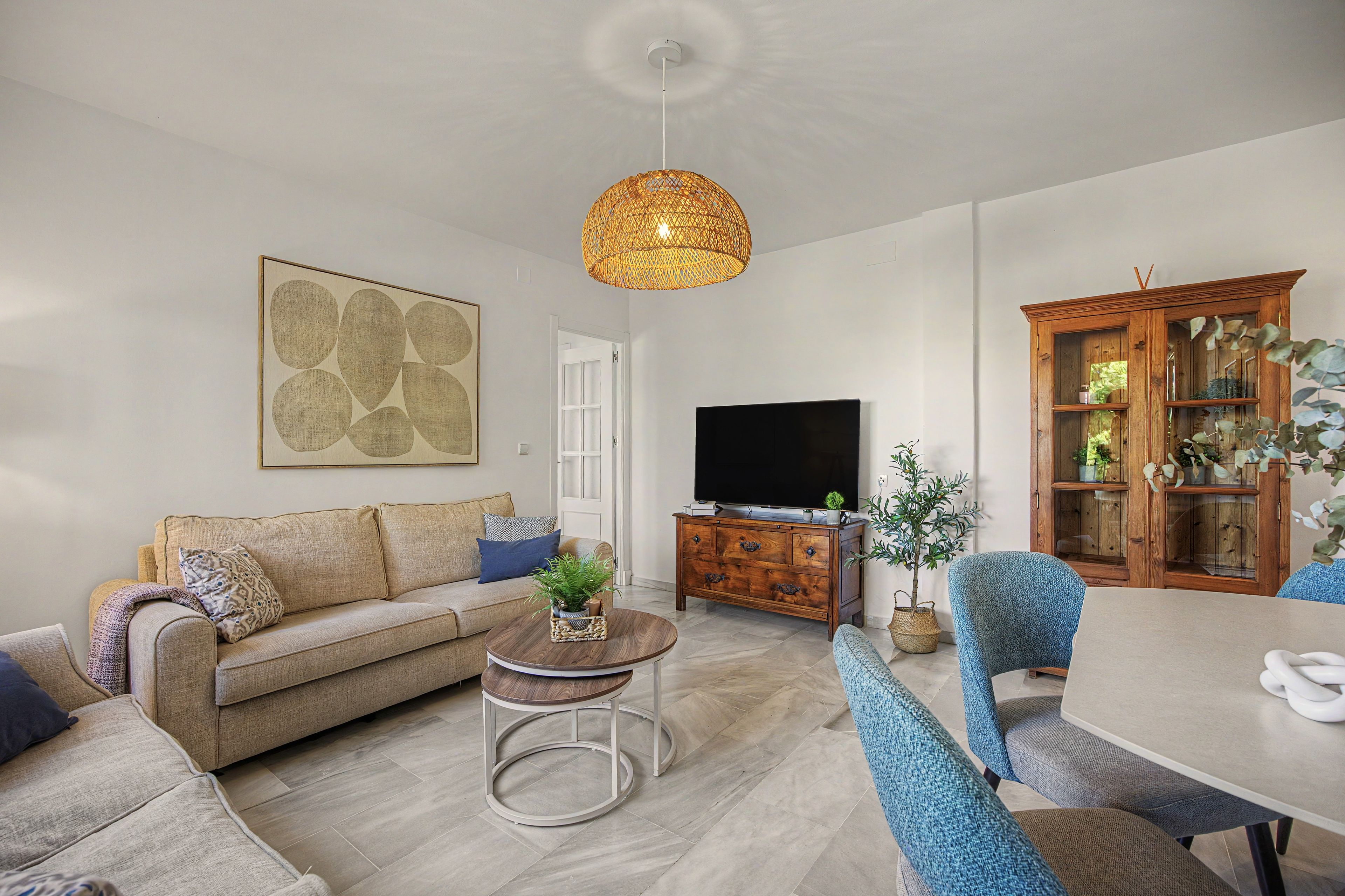 Sala de estar com sofá, mesa de centro, televisão e área de jantar com cadeiras.