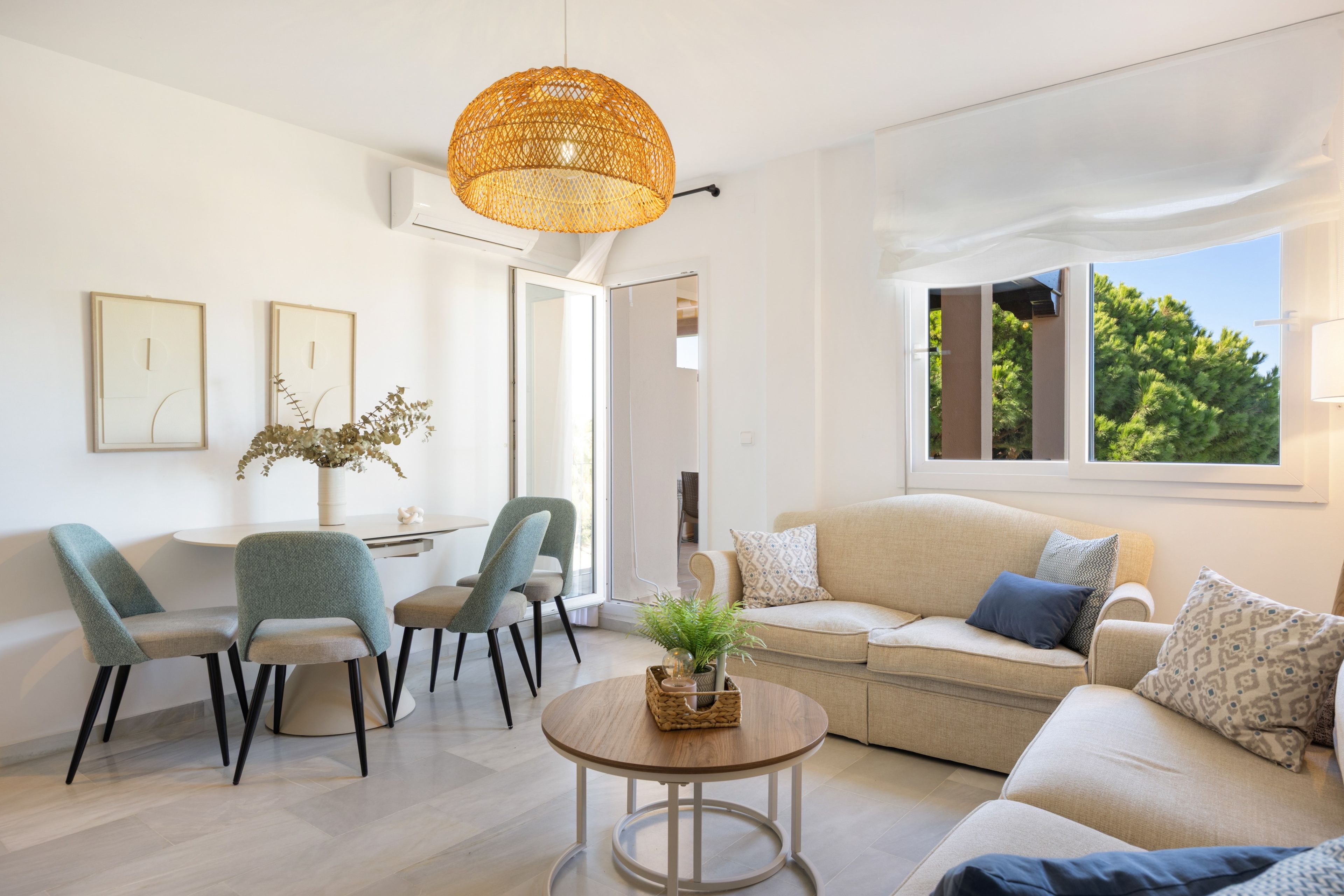 A modern living room with a sofa, chairs, a coffee table, and a hanging light fixture.