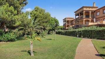 A well-maintained garden with a paved walkway leading to a multi-story building with balconies.