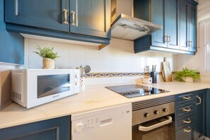Een keuken met een magnetron, fornuis, oven en kasten.
