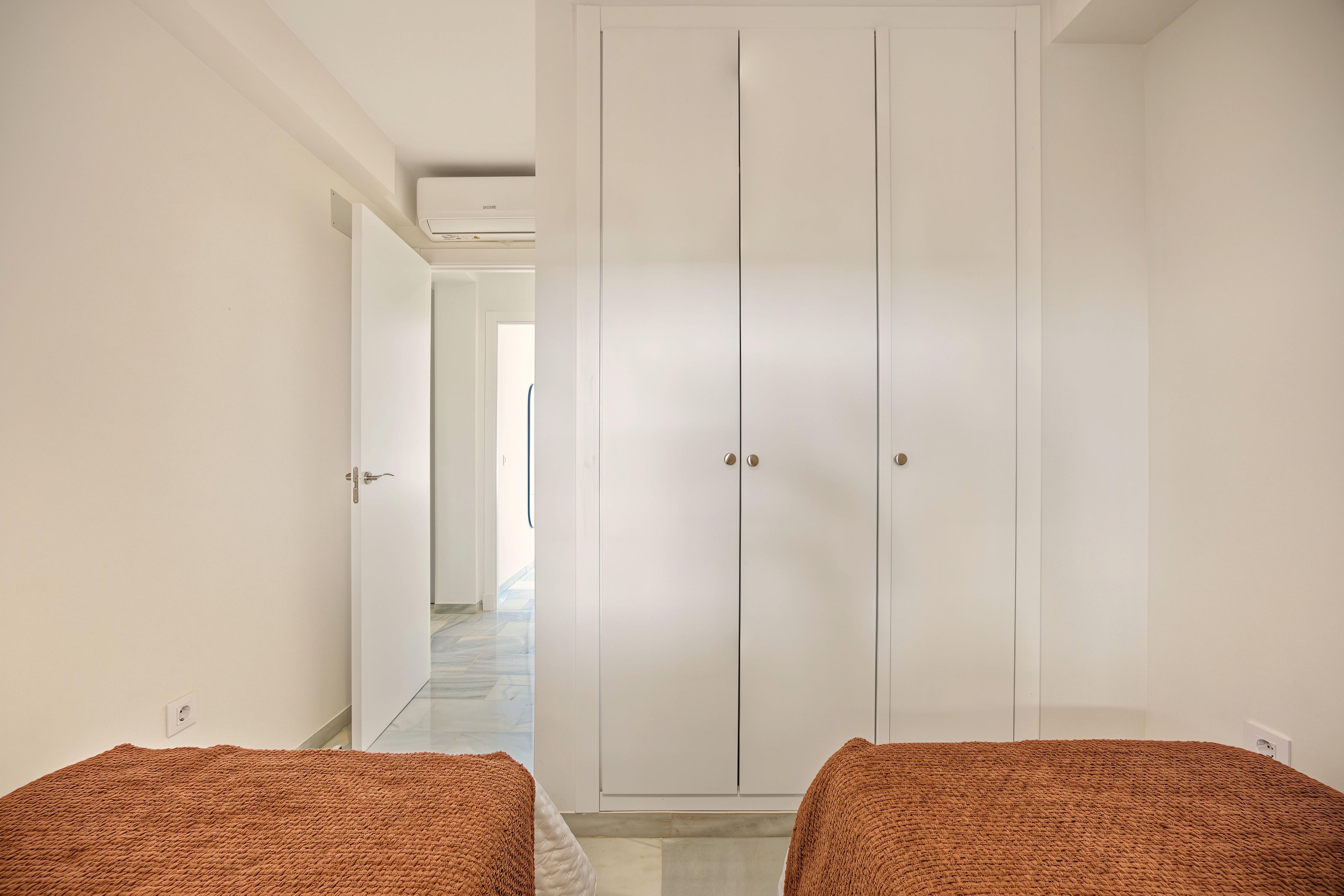 Un pasillo con un armario, una cama y una puerta que da a otra habitación.