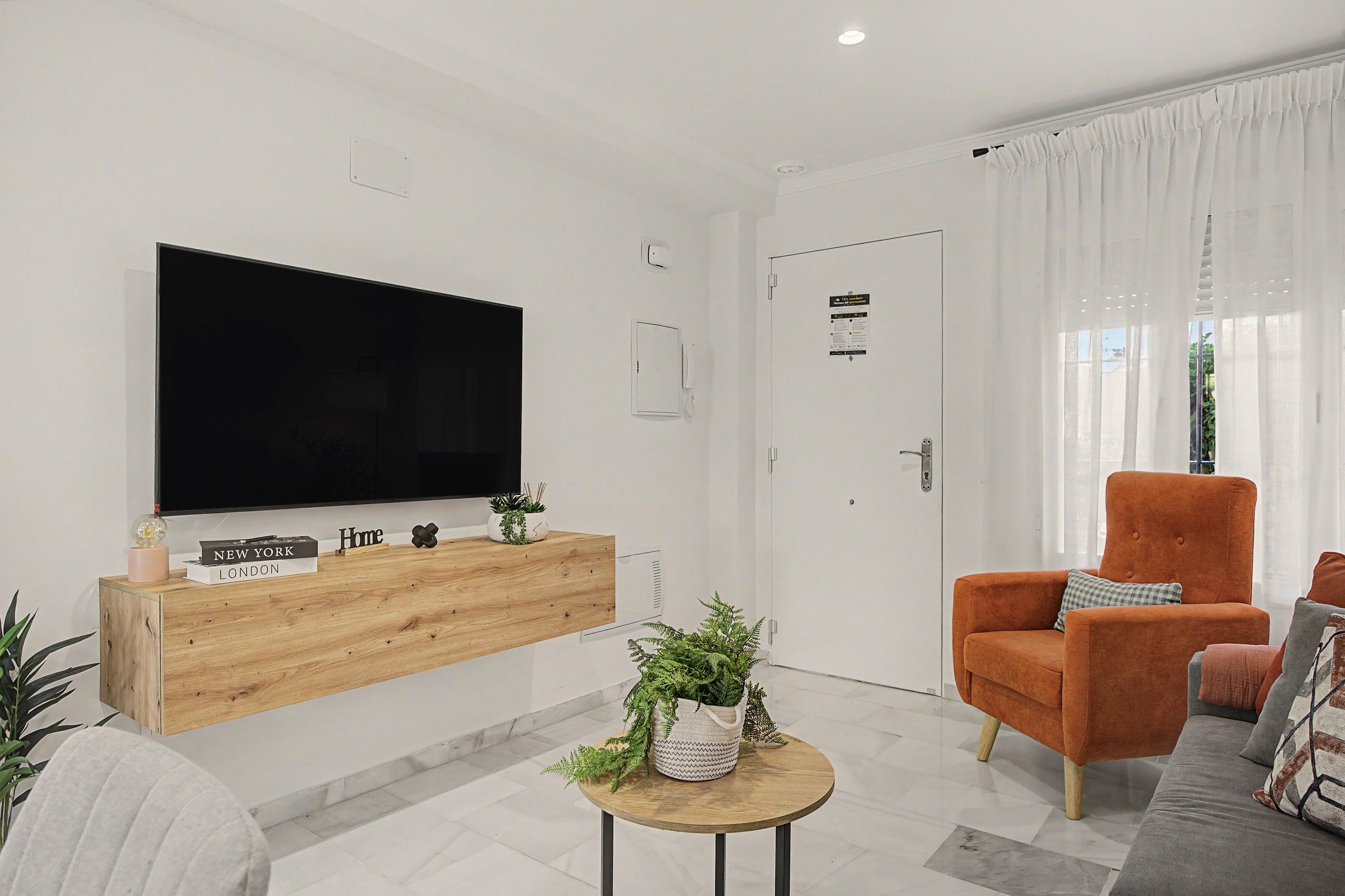 Uma sala de estar moderna com televisão de tela plana, console de madeira e área de estar.