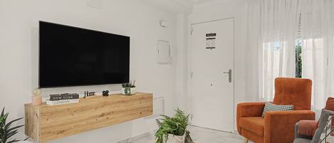 Uma sala de estar moderna com televisão de tela plana, console de madeira e área de estar.