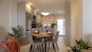 Cocina moderna con comedor, que incluye una mesa redonda, sillas y una lámpara colgante.