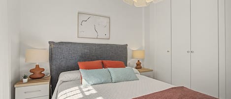 A neatly arranged bedroom with a bed, bedside tables, a hanging light fixture, and a wall-mounted artwork.