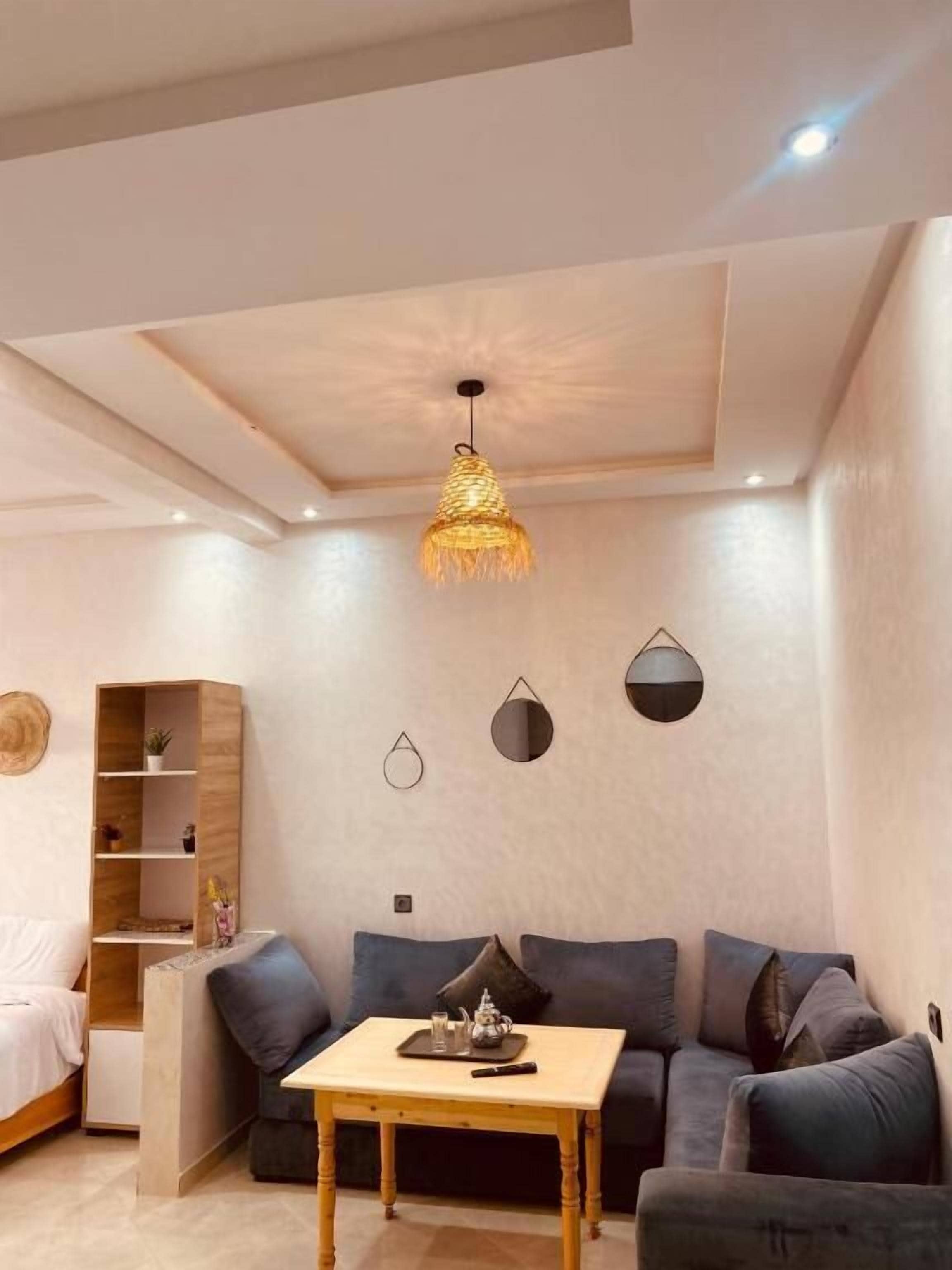 A modern living room with a sofa, a wooden table, and a hanging light fixture.