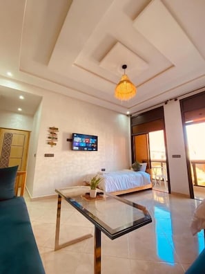 A modern hotel room with a bed, a glass coffee table, a television, and a large window. - WOW beach house (Imsouane)
