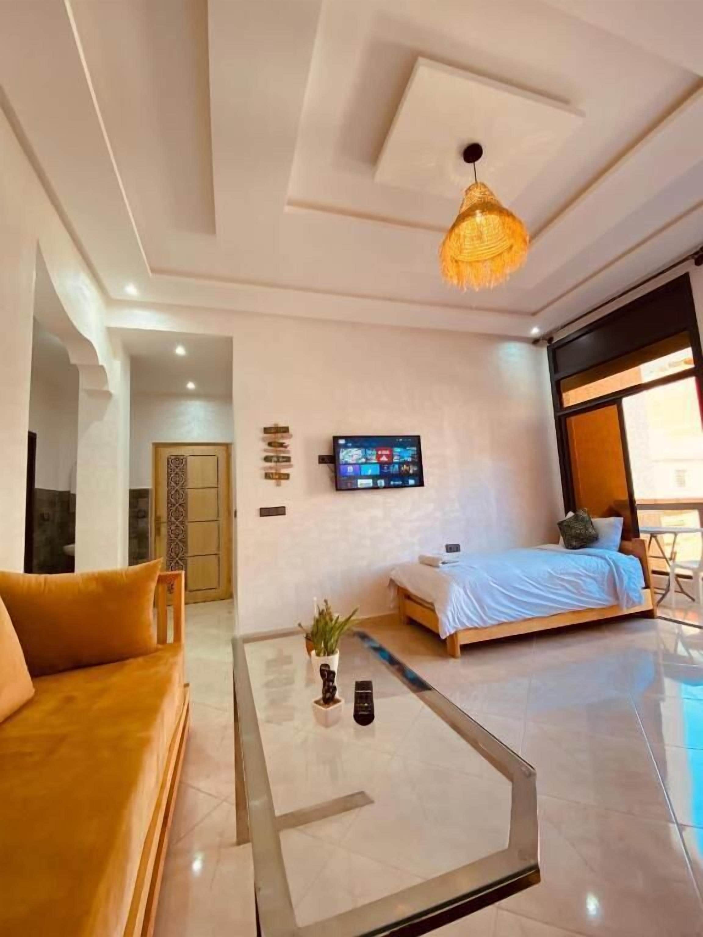 Habitació d'hotel moderna amb un sofà, un llit, una taula de cafè, un televisor i una finestra gran.