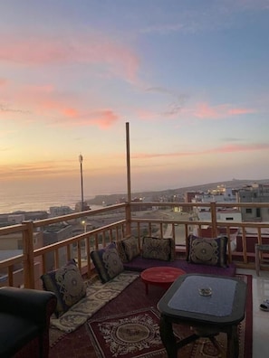 Un balcón con vista al mar, una mesa y asientos.