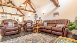A spacious living room with leather sofas, a coffee table, and a board game. - Barn stay with Mountain and Estuary views | Beudy-Talsarnau (Talsarnau)