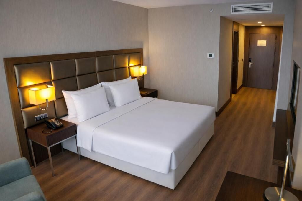Une chambre d’hôtel avec un grand lit, des lampes de chevet, une table de nuit, une chaise et un téléviseur.