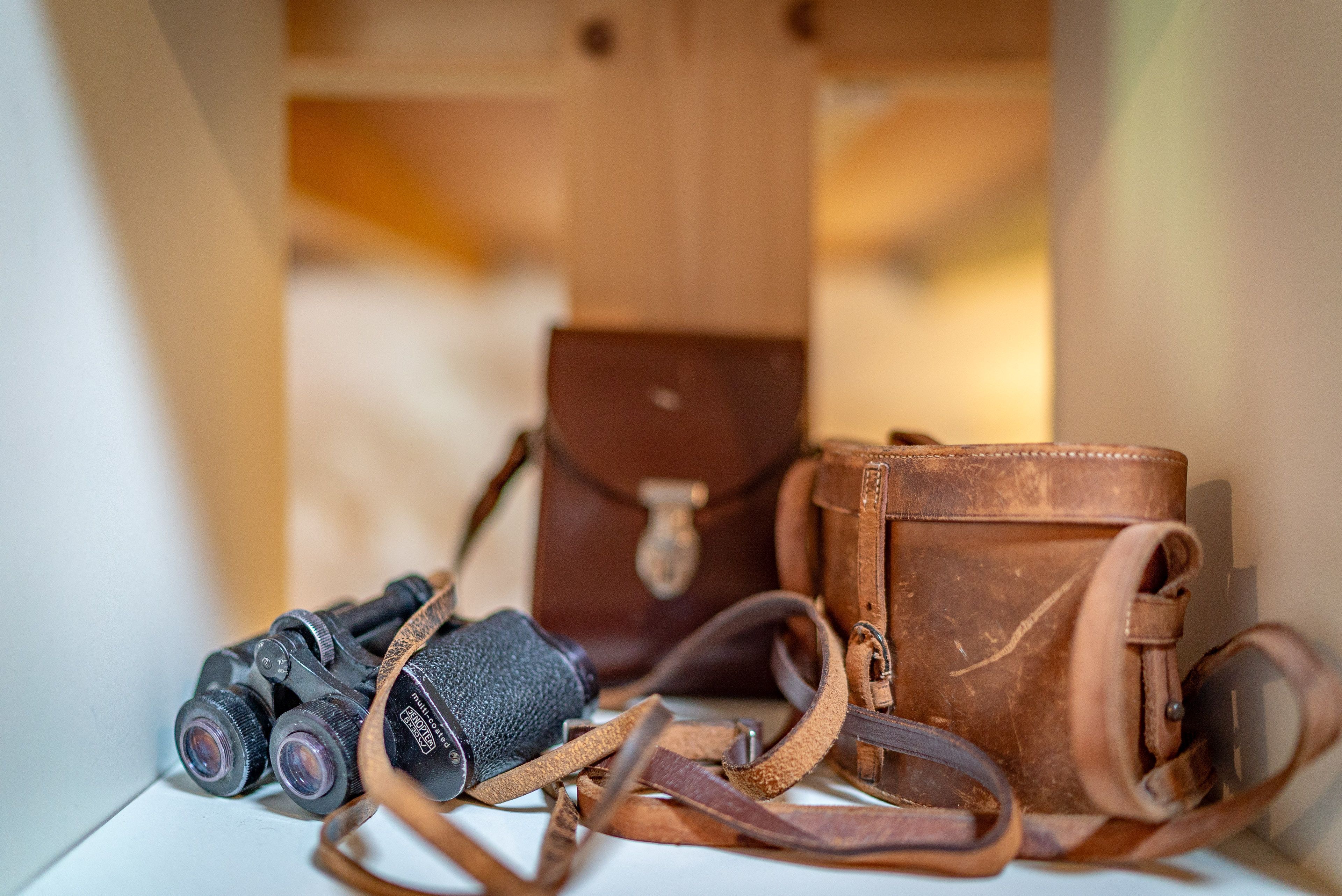 A camera and a leather bag on a white surface.