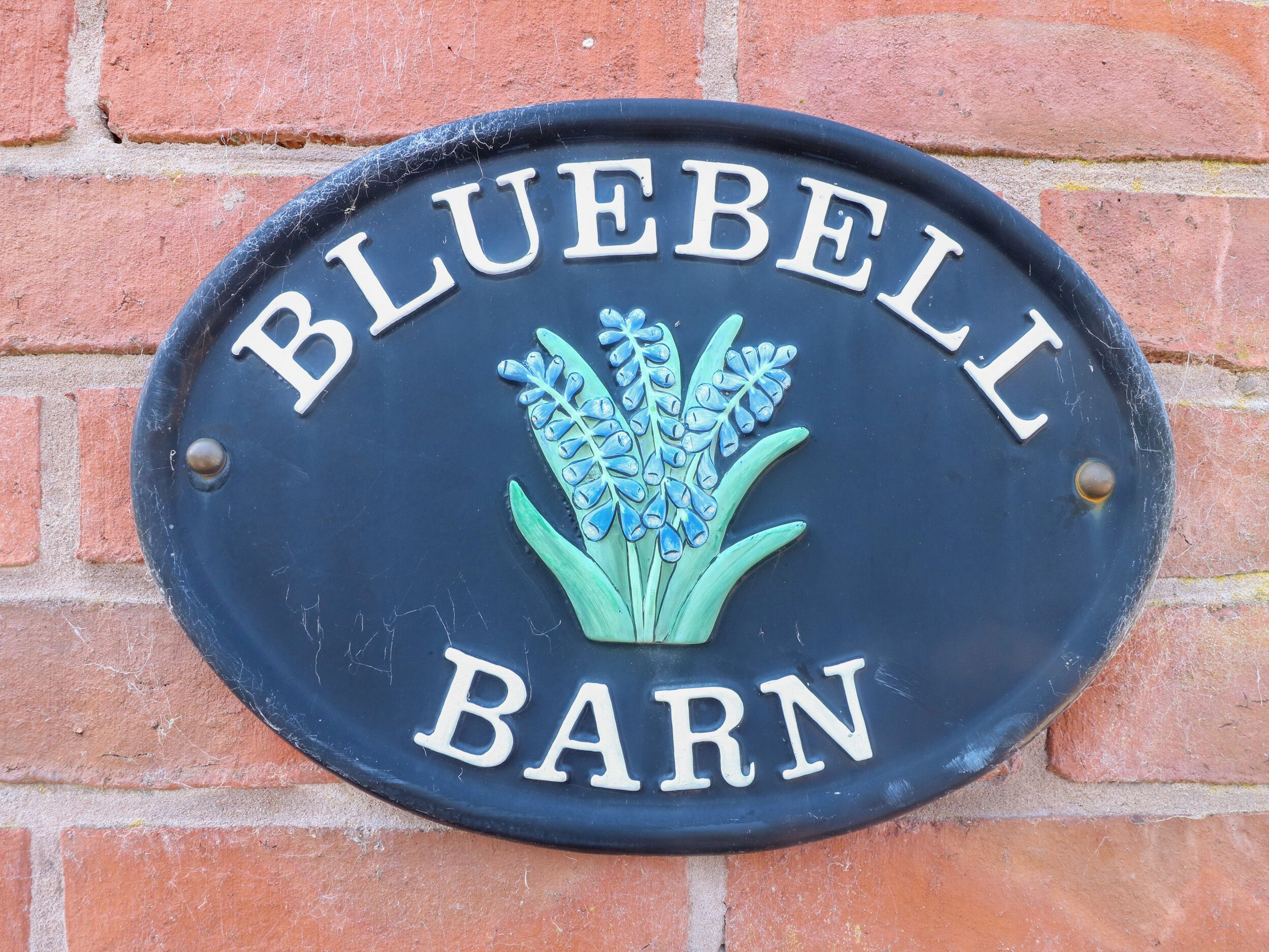A blue plaque with 'BLUEBELL BARN' and a floral design.