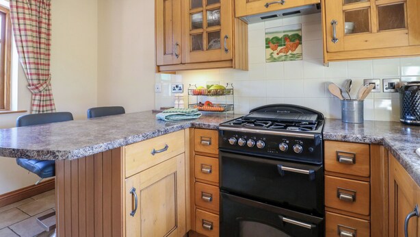 Una cocina con armarios de madera, una estufa y un comedor con sillas.