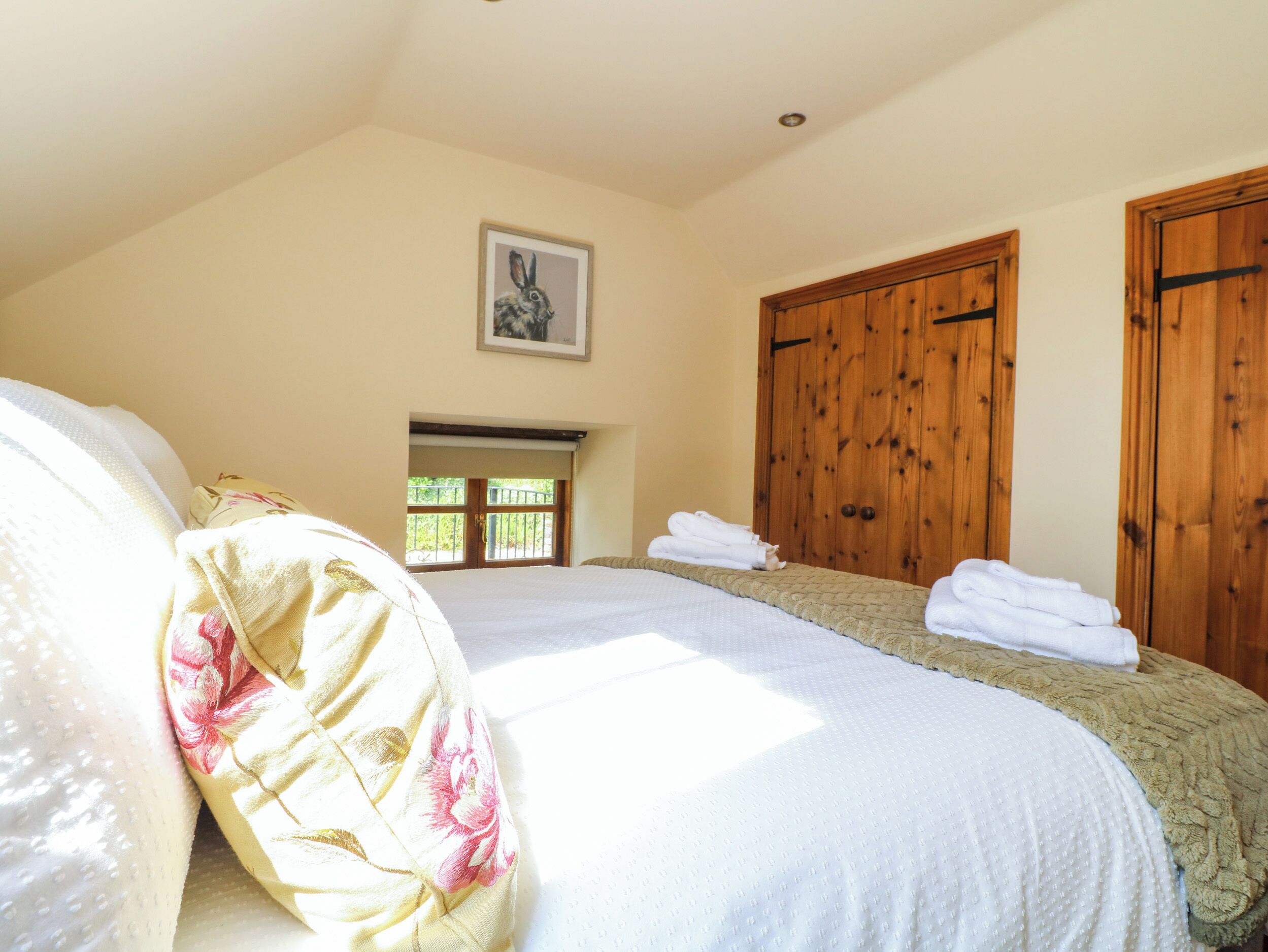 A bedroom with a large bed, wooden wardrobe, and a framed picture on the wall.
