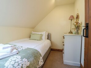 A bedroom with a bed, a dresser, and a nightstand with lamps.