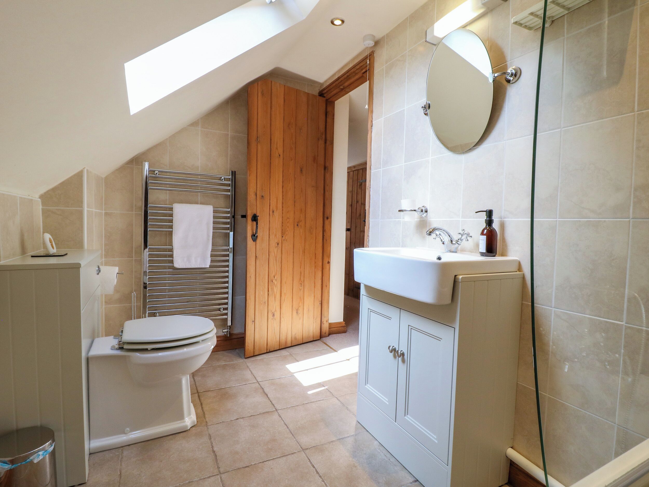 A bathroom with a toilet, a sink, a mirror, and a shower area.