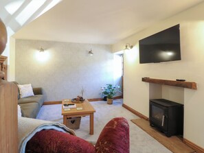 Una sala de estar con un sofá, una mesa de centro, una chimenea, un televisor y una planta en maceta.