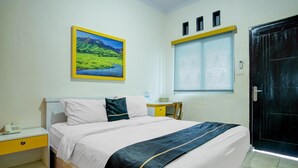 A hotel room with a bed, a nightstand, a desk, a window, and a door. - Lima Residence Cozy Double (Bandar Lampung)
