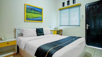 A hotel room with a bed, a nightstand, a desk, a window, and a door.