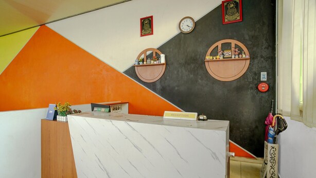 A reception desk with a 'RECEPTION' sign, two wall-mounted clocks, and a small shelf with decorative items. - Lima Residence Cozy Double (Bandar Lampung)