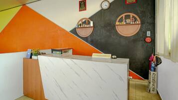 A reception desk with a 'RECEPTION' sign, two wall-mounted clocks, and a small shelf with decorative items.
