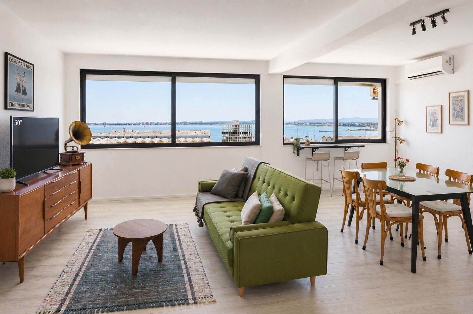 Un salon moderne avec un canapé vert, un téléviseur et un coin repas comprenant une table et des chaises.