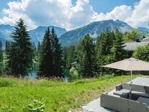 Une terrasse dotée de mobilier d’extérieur et offrant une vue sur un lac et des montagnes.