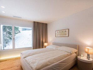 Ein Hotelzimmer mit großem Fenster, einem Bett, zwei Nachttischen und einem Wandbild.
