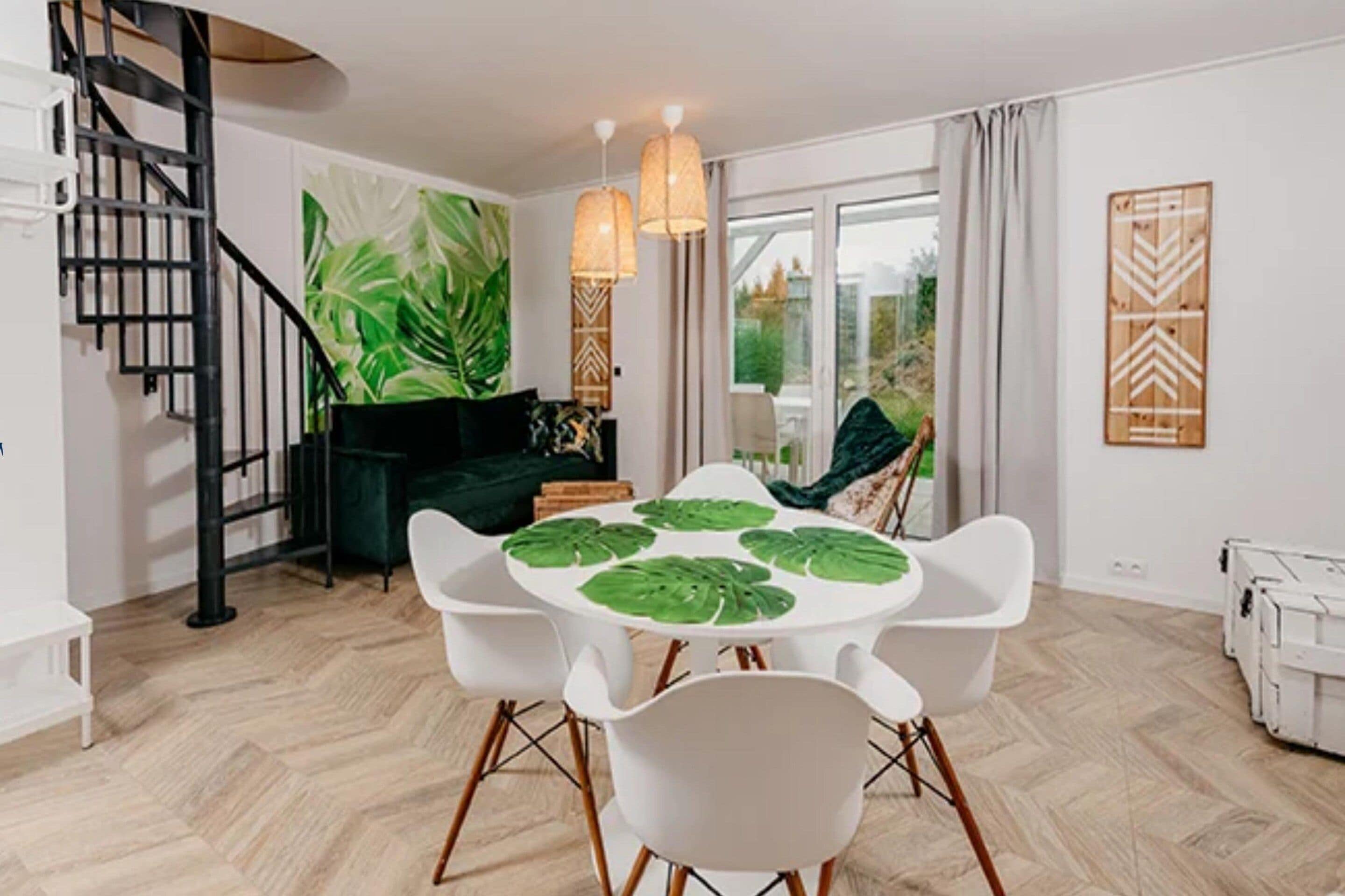 A dining area with a round table, white chairs, and a green plant centerpiece.