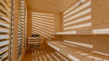 Una sauna con listones de madera en las paredes y el techo, un banco y una pequeña mesa con un cubo.