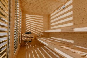 Una sauna con listones de madera en las paredes y el techo, un banco y una pequeña mesa con un cubo.