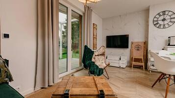 Una sala de estar moderna con una mesa de centro de madera, un sofá, un televisor y un comedor con una silla y una mesita.