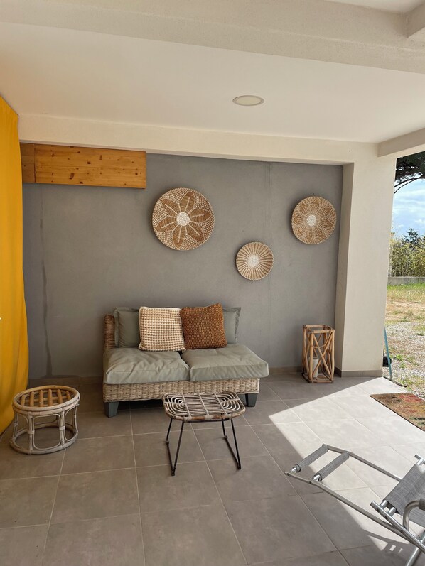 Ein modernes Interieur mit einem grauen Sofa, Korbmöbeln und Wanddekoration.