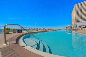 Ein Pool mit gewölbter Kante, einem Metallgeländer und einem gepflasterten Weg.