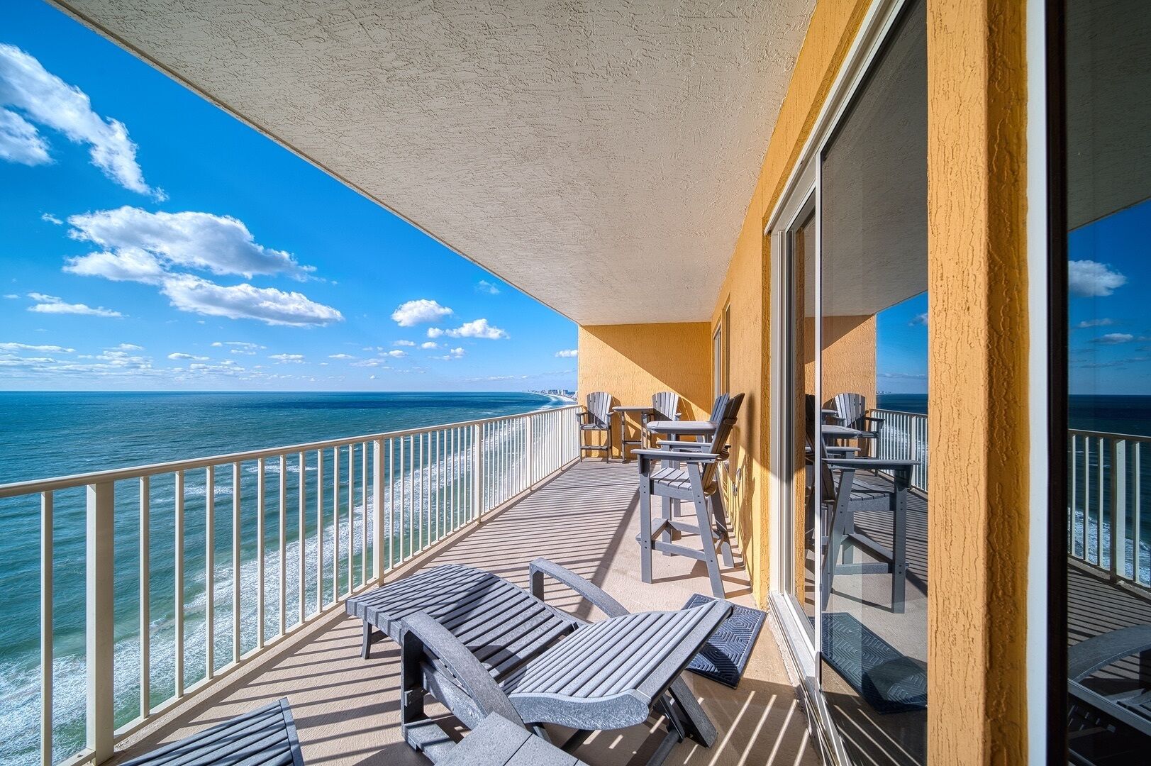 A balcony with a view of the ocean, equipped with outdoor furniture and a railing.