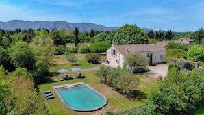 Una casa con piscina, rodeada de abundante vegetación y montañas al fondo.