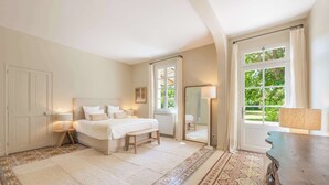 Un dormitorio con cama, lámparas de noche, un espejo, una ventana con cortinas y una alfombra estampada.