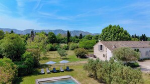 Una villa con piscina, mobiliario exterior y vistas a las montañas.