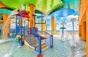 Un espace de parc aquatique comprenant des toboggans, des jets d’eau et une piscine.